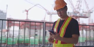 建筑工人亚洲人用智能手机操作。控制工人建造一座大楼。6、安全帽，防止事故发生。电话会议在工作