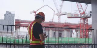 建筑工人亚洲人用智能手机操作。控制工人建造一座大楼。6、安全帽，防止事故发生。电话会议在工作