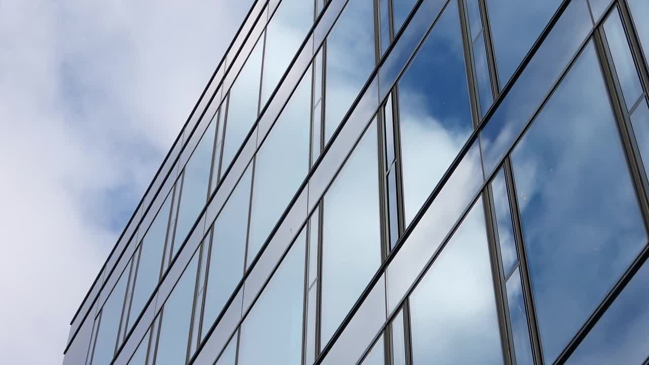 蓝色的夏日天空，云朵反射在办公大楼的玻璃幕墙上