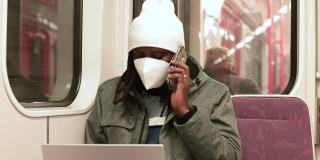 非洲人把电话放在耳边，听信息。脸上戴着口罩。
