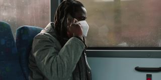 戴面具的非洲人在公共汽车上打电话。他拿着电话，说留言。