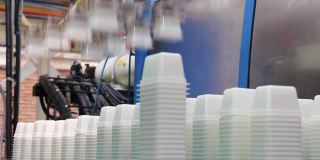 白色塑料容器由自动化机器放置在工厂的传送带上