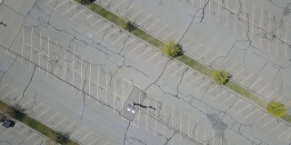 无人机飞过空旷的停车场，空旷而寂寞，旧柏油路