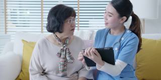 年轻的亚洲女性护士，辅助生活，家庭护理员或医生在家里拜访老年人，在平板电脑上在线谈论结果跟踪检查表，保健建议或处方。