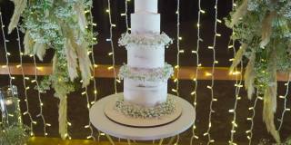 华丽的白色婚礼蛋糕装饰鲜花和浪漫的灯光背后
