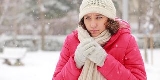 年轻女子感到寒冷，在寒冷和下雪的冬日