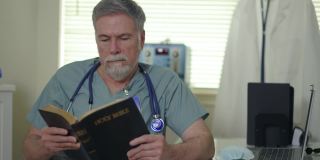 在一个小诊所里，一位基督教医生坐在他的办公桌前阅读《圣经》，以寻求鼓励和安慰。