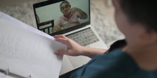 亚裔华裔女医生在家工作，在客厅用笔记本电脑咨询她的成年病人