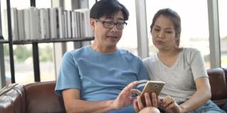 亚洲老年夫妇在家里用智能手机打视频电话