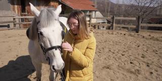 可爱的有爱心的年轻女子，在动物救援中心爱抚和亲吻白色种马