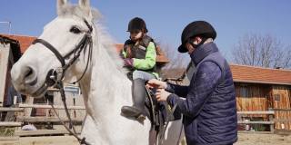 兴奋的女孩，学习如何骑马，同时参观动物救援中心协会