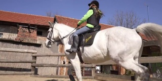 勇敢的女孩在动物救援中心骑着白马享受宁静的时刻