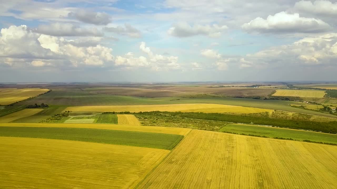 空中的乡村景观，点缀着黄色的农田和蓝天白云。