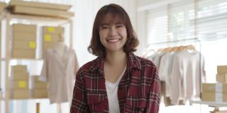 肖像年轻迷人的亚洲女企业主创业看相机工作开心用纸箱在家里准备快递在中小企业供应链，采购，全渠道电商在线概念。
