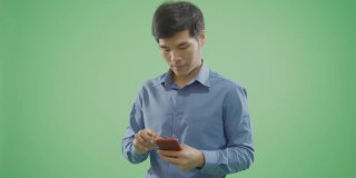 绿色背景的帅哥在智能手机上发短信慢动作。