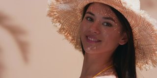 年轻的美模特戴着草帽，转身享受阳光