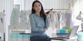 肖像年轻迷人的亚洲女企业主创业看相机工作开心用盒子在家准备包裹快递中小企业供应链，采购，全渠道商务在线概念。
