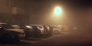 黑暗中有雾的四合院。住所附近的停车场。路灯闪亮的