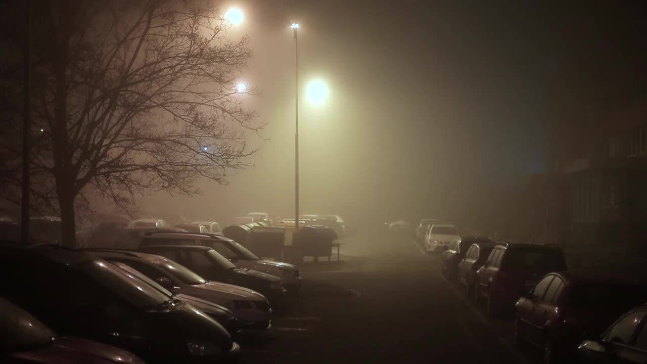 城市主义，雾，傍晚建筑物附近的停车场，城市灯光照亮