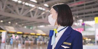 新冠肺炎疫情期间，戴口罩的空乘人员在机场候机楼步行前往飞机，以预防新冠肺炎感染。航空运输的新常态生活理念。