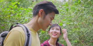 年轻的亚洲男人和女人朋友一起在森林里旅行。情侣们在大自然中感受清新和放松，看着窗外的风景，然后带着幸福和乐趣继续散步。