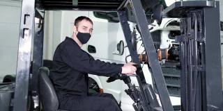 维修车间装载机操作工戴防护面罩工作。