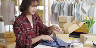 年轻有吸引力的美丽时髦的亚洲女性包装产品小商包裹订购网上零售商店交付给客户。中小企业业主工作准备dropshipping箱在家办公室。
