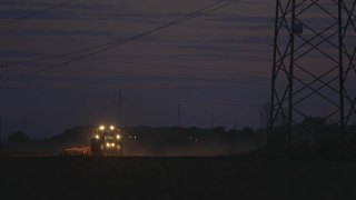 SLO MO拖拉机在夜间的电塔下犁地视频素材模板下载