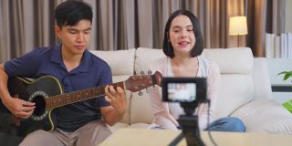 一对有影响力的短视频歌手表演音乐和女孩唱歌秀给在家收听的网络观众。男人弹吉他，女人唱歌。家庭娱乐和博客的概念