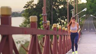 亚洲年轻健康的运动女人在公园里跑步和慢跑在锻炼期间感觉不舒服。这个女孩感到肚子痛。由于胃痛，她停止了运动。疾病和保健概念。视频素材模板下载