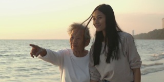 一位老年妇女和她的女儿在海滩上散步。