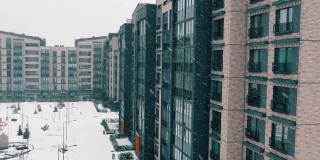 冬季景观与公寓大楼。多层住宅立面，庭院中雪花飘飘的景象。建筑城市住宅，房地产代理在现代，新，时尚的城市概念。