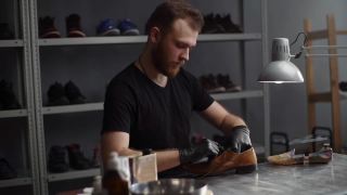 手持式拍摄的鞋匠解开鞋带在磨损的浅棕色皮鞋上要修理。视频素材模板下载