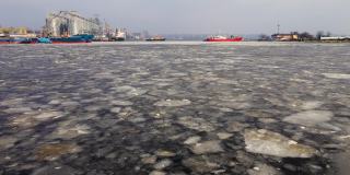 无人机拍摄的国际货运港正在融冰，码头上的船舶和码头起重机以及钢粮储存罐正在融化