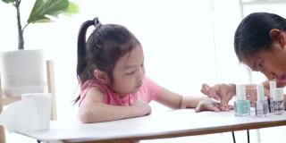 快乐的亚洲儿童涂指甲油，同时放松在一个家，生活理念。