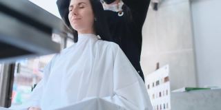 亚洲美容院的女理发师在白天用轻松愉快的心情为白种顾客梳理头发