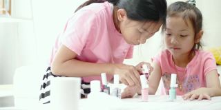 快乐的亚洲儿童涂指甲油，同时放松在一个家，生活理念。