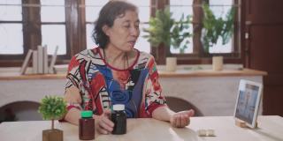 远程医疗的亚洲老年病人女性和孙女使用笔记本电脑视频电话与女医生，护士在家里的客厅