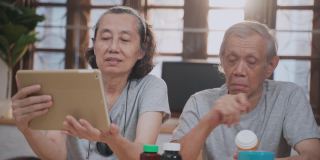 生病的亚洲资深夫妇通过视频远程医疗电话咨询医生在家