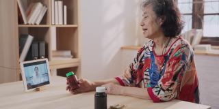 远程医疗的亚洲老年病人女性和孙女使用笔记本电脑视频电话与女医生，护士在家里的客厅
