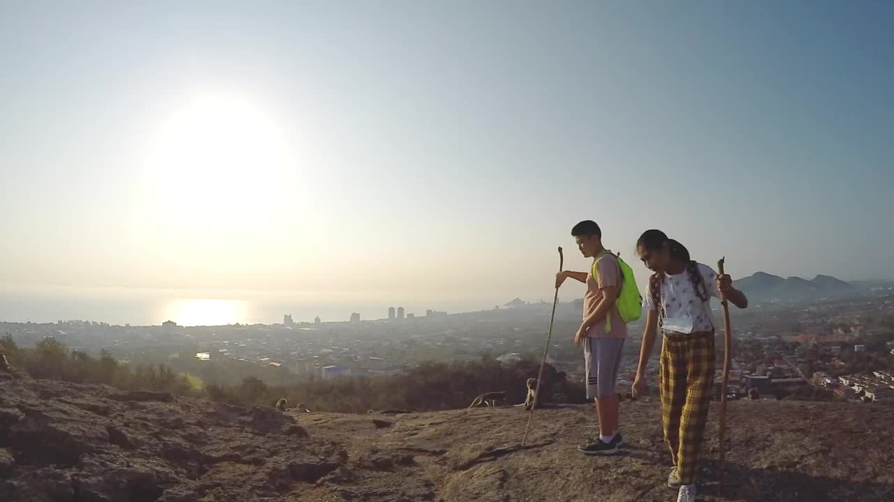 快乐的亚洲背包客孩子们在山顶奔跑，举起双手，用阳光看风景，生活理念。