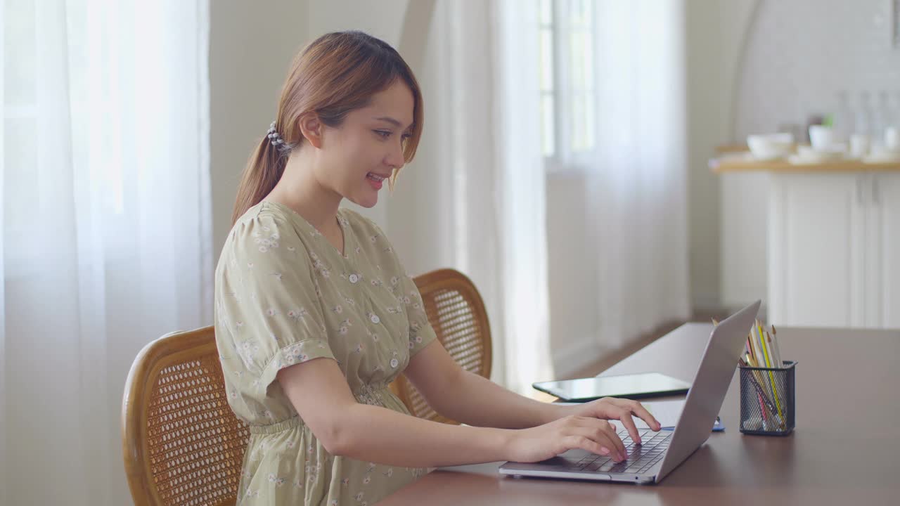 亚洲孕妇在家使用笔记本电脑工作