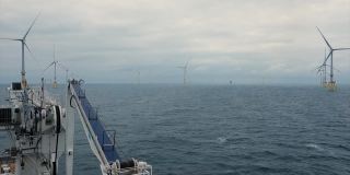 从转运船(船，码头)的平台上看，漂浮在风力发电机，蓝色波浪的海和穆迪。起重机和甲板上的视图。