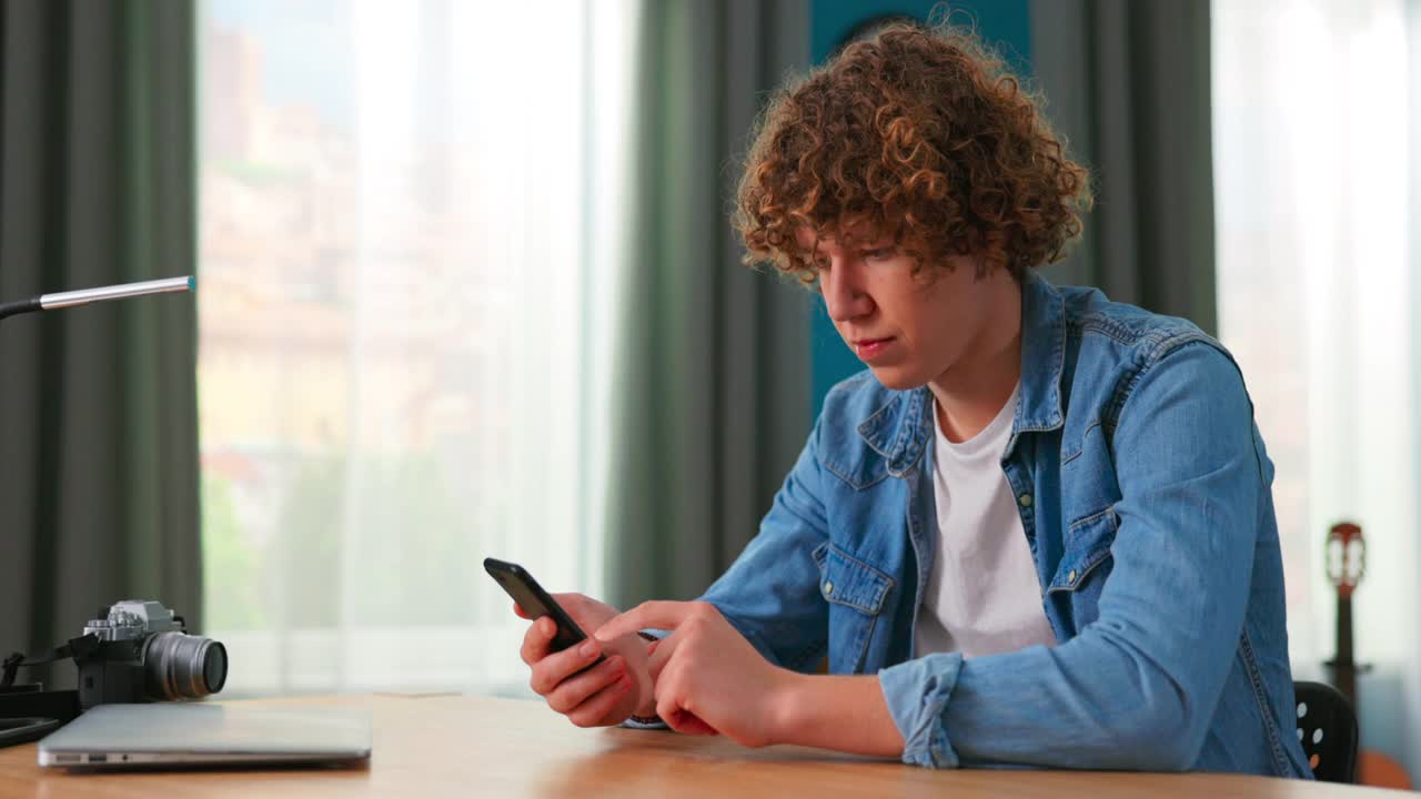 十几岁的男孩在家里用智能手机。白人少年用手机在社交网络上消磨时间。白人年轻人用手机玩游戏。生活方式的概念