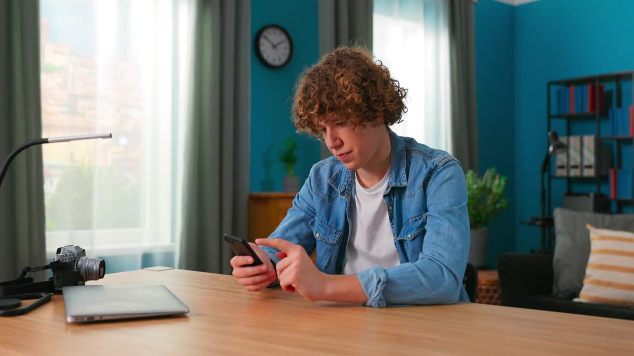 十几岁的男孩在家里用智能手机。白人少年用手机在社交网络上消磨时间。白人年轻人用手机玩游戏。生活方式的概念