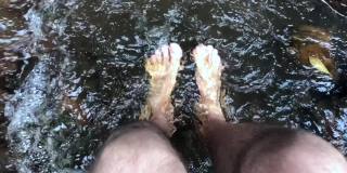 一个人在河里看着自己的脚。