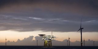 海上风电场的戏剧性的观点，风力发电机与变电站在水平在日落，波浪的海和穆迪，戏剧性的(红色)天空。德国,Borkum Riffgrund