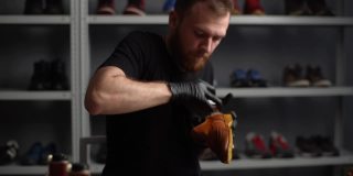 肖像的专业鞋匠在黑色手套抛光浅棕色皮鞋与刷子。