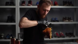肖像的专业鞋匠在黑色手套抛光浅棕色皮鞋与刷子。视频素材模板下载
