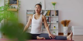 平静的迷人的亚洲女人练习瑜伽，侧身伸展的姿势在卧室里冥想，早上醒来后感觉如此舒适和放松，保健理念